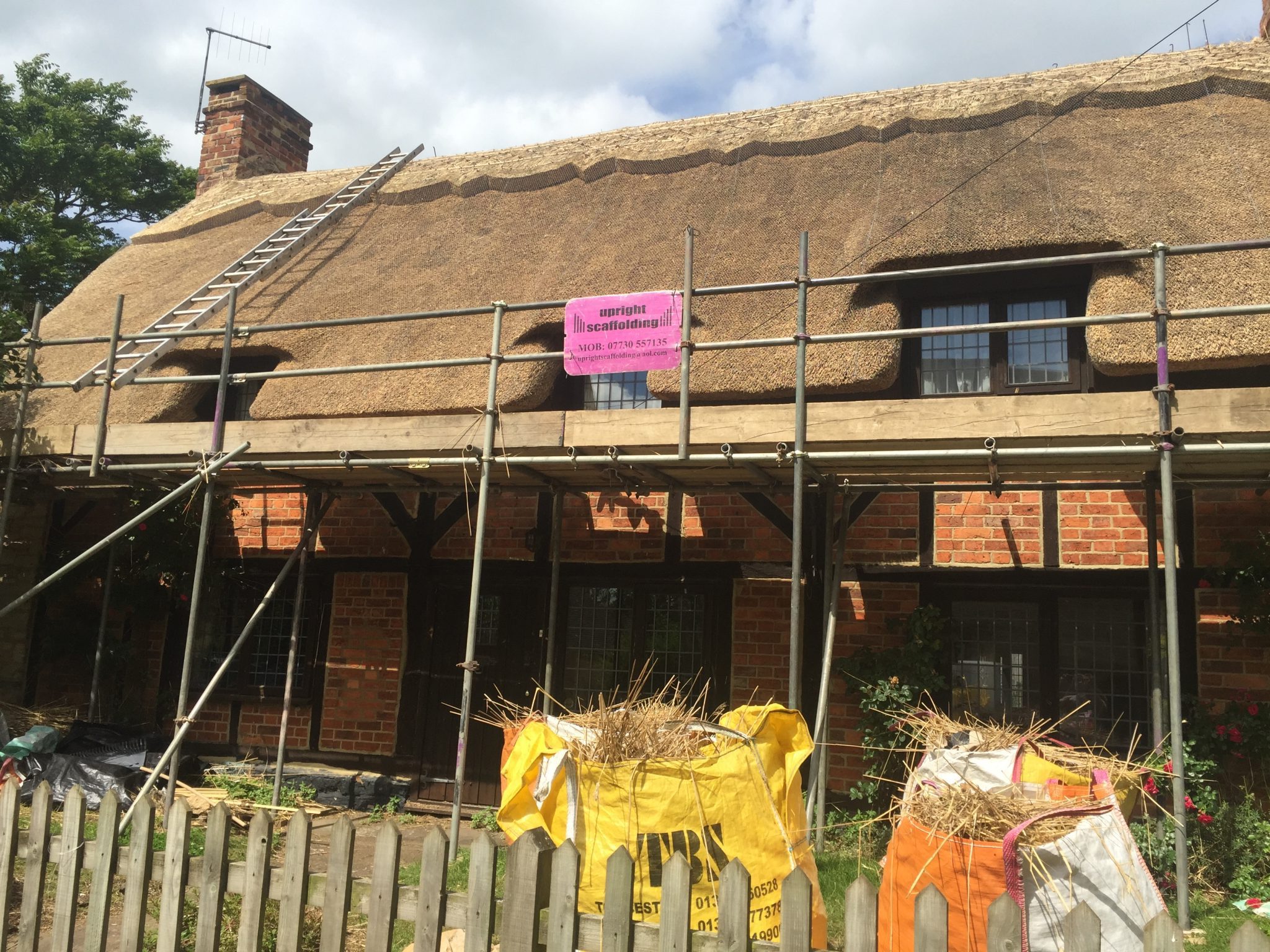 water reed thatched roof on brick house with scaffolding